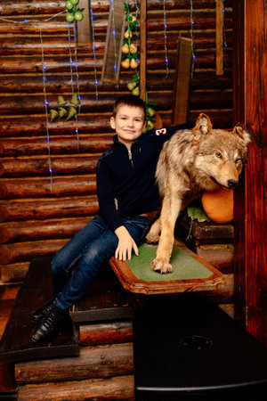 Boy posing with stuffed wolf in wooden house