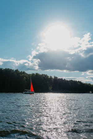 Sunny day on the lake with a red sailboat
