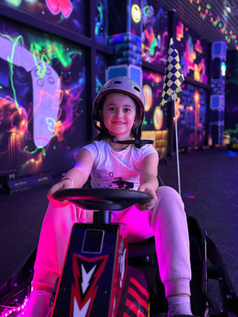 Girl smiling in helmet driving go-kart at neon arcadeの写真素材