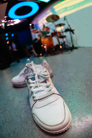 White sneakers on stage with drums and neon lights