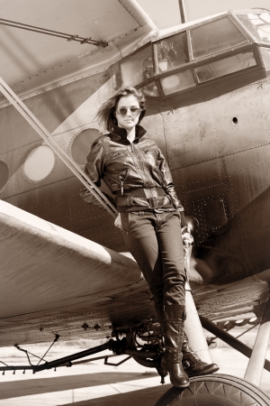 Beautiful girl in black jacket standing on a war aircraft   の写真素材