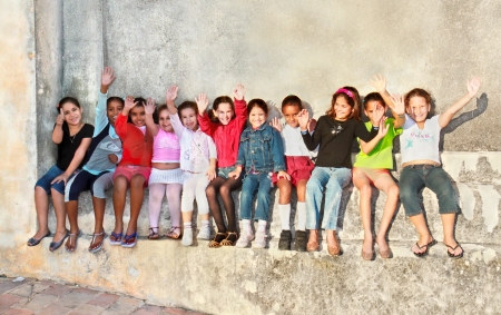 TRINIDAD, CUBA -13 JANUARY: Unidentified Cuban multi-ethnic group of  girls  are sitting and arms raised on the main street of Trinidad on January 13. 2010. Trinidad, Cuba.のeditorial素材