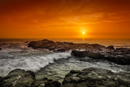 beautiful sunset on the sea with rocks and wavesの写真素材