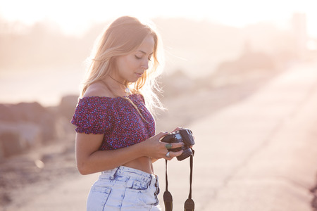 Young woman checks her camera after taking pictures on the beachの写真素材