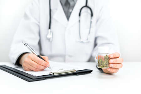 Doctor prescribes CBD for pain relief and healing. Doc holds medical marijuana in hand, offers medical cannabis, legal light medication, alternative remedies or medicines, medicine concept to patientの写真素材