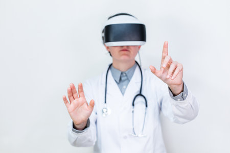 Doctor checks medical data on medical records while using virtual reality glasses. He treats a patient with VR headset glasses device. white isolated background. Medicine and Health Conceptの写真素材