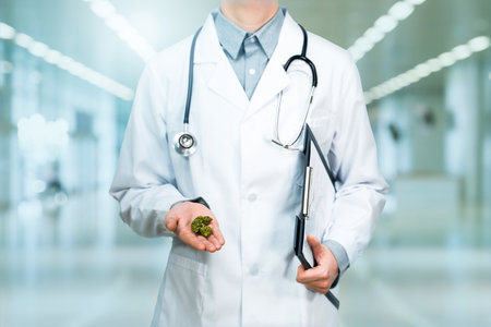 Doctor with medical cannabidiol CBD cannabis marijuana with hospital in the background. Alternative, natural, legal medicine for pain. Legal medical marijuana for healthcare.の写真素材
