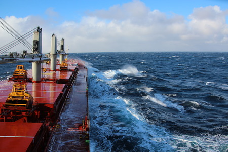 Movement of the vessel in stormy weather, Pacific Ocean. Waves and spray covering the ship during a stormの写真素材