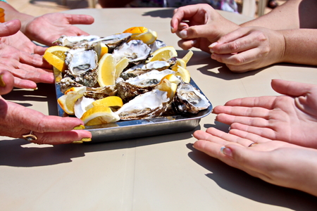 Fresh oysters with lemon lying on a platter and plate as delicaciesの写真素材