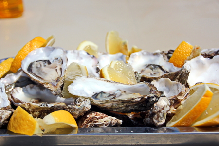 Fresh oysters with lemon lying on a platter and plate as delicaciesの写真素材