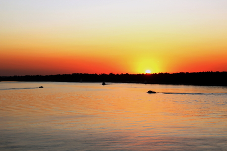 Sunset on the Mississippi River, New Orleans Port, USA. Colorful sunset against the sky, water and river bank.の写真素材