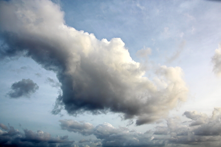 The clouds are multicolored, thunderous bizarre shapes against the blue sky and the sun above the ocean surface. The game of light and shadows in various variations of sunlight illumination of clouds and sky.の写真素材