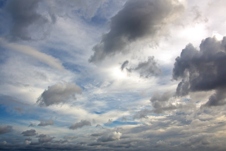 The clouds are multicolored, thunderous bizarre shapes against the blue sky and the sun above the ocean surface. The game of light and shadows in various variations of sunlight illumination of clouds and sky.の写真素材