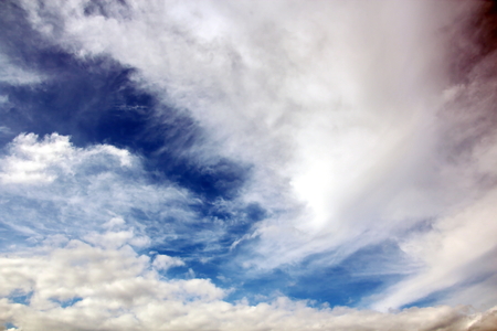 The clouds are multicolored, thunderous bizarre shapes against the blue sky and the sun above the ocean surface. The game of light and shadows in various variations of sunlight illumination of clouds and sky.の写真素材