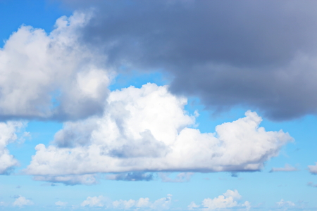 The clouds are multicolored, thunderous bizarre shapes against the blue sky and the sun above the ocean surface. The game of light and shadows in various variations of sunlight illumination of clouds and sky.の写真素材