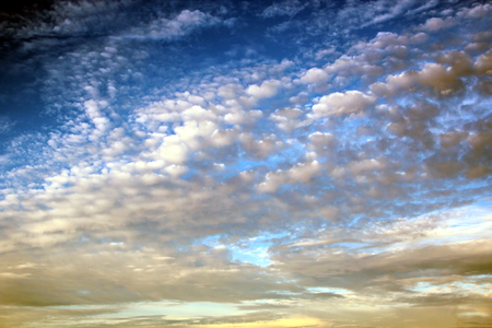 The clouds are multicolored, thunderous bizarre shapes against the blue sky and the sun above the ocean surface. The game of light and shadows in various variations of sunlight illumination of clouds and sky.の写真素材