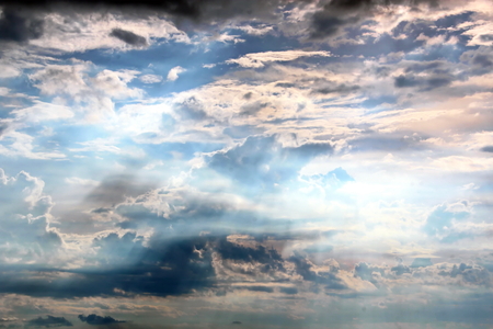The clouds are multicolored, thunderous bizarre shapes against the blue sky and the sun above the ocean surface. The game of light and shadows in various variations of sunlight illumination of clouds and sky.の写真素材