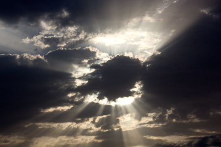 The clouds are multicolored, thunderous bizarre shapes against the blue sky and the sun above the ocean surface. The game of light and shadows in various variations of sunlight illumination of clouds and sky.の写真素材