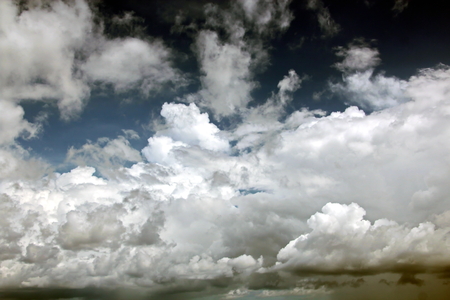 The clouds are multicolored, thunderous bizarre shapes against the blue sky and the sun above the ocean surface. The game of light and shadows in various variations of sunlight illumination of clouds and sky.の写真素材