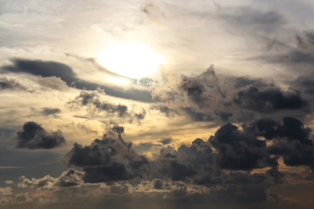 The clouds are multicolored, thunderous bizarre shapes against the blue sky and the sun above the ocean surface. The game of light and shadows in various variations of sunlight illumination of clouds and sky.の写真素材