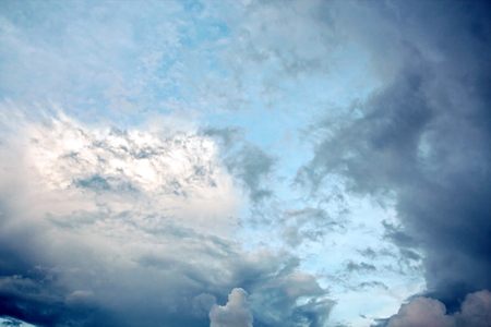 The clouds are multicolored, thunderous bizarre shapes against the blue sky and the sun above the ocean surface. The game of light and shadows in various variations of sunlight illumination of clouds and sky.の写真素材