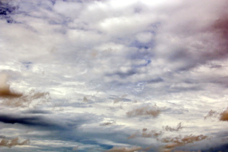 The clouds are multicolored, thunderous bizarre shapes against the blue sky and the sun above the ocean surface. The game of light and shadows in various variations of sunlight illumination of clouds and sky.の写真素材