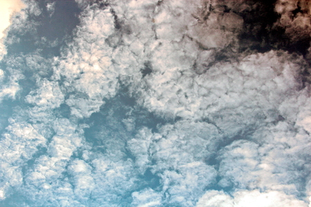 The clouds are multicolored, thunderous bizarre shapes against the blue sky and the sun above the...