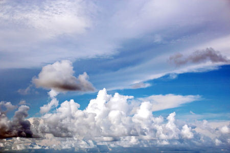 The clouds are multicolored, thunderous bizarre shapes against the blue sky and the sun above the ocean surface. The game of light and shadows in various variations of sunlight illumination of clouds and sky.の写真素材