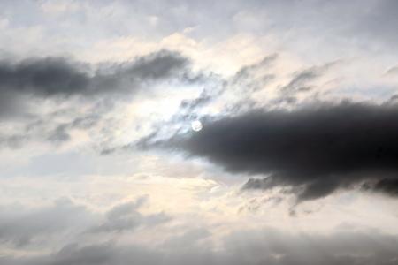 The clouds are multicolored, thunderous bizarre shapes against the blue sky and the sun above the ocean surface. The game of light and shadows in various variations of sunlight illumination of clouds and sky.の写真素材