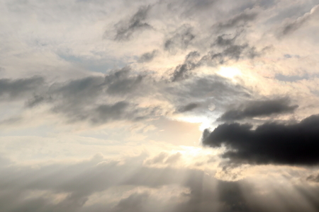 The clouds are multicolored, thunderous bizarre shapes against the blue sky and the sun above the ocean surface. The game of light and shadows in various variations of sunlight illumination of clouds and sky.の写真素材