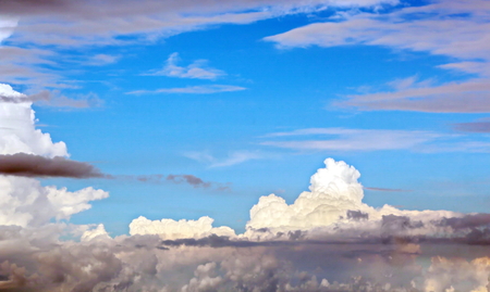 The clouds are multicolored, thunderous bizarre shapes against the blue sky and the sun above the ocean surface. The game of light and shadows in various variations of sunlight illumination of clouds and sky.の写真素材