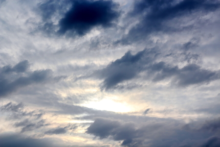 The clouds are multicolored, thunderous bizarre shapes against the blue sky and the sun above the ocean surface. The game of light and shadows in various variations of sunlight illumination of clouds and sky.の写真素材