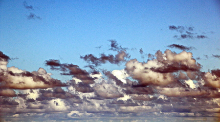 The clouds are multicolored, thunderous bizarre shapes against the blue sky and the sun above the...