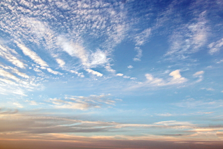 The clouds are multicolored, thunderous bizarre shapes against the blue sky and the sun above the ocean surface. The game of light and shadows in various variations of sunlight illumination of clouds and sky.の写真素材