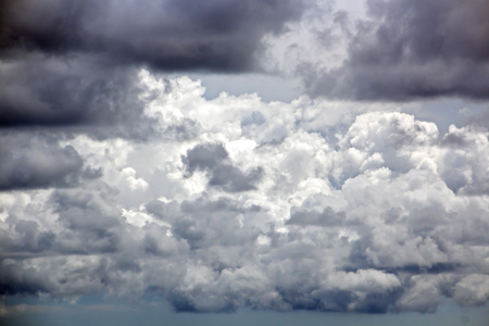 The clouds are multicolored, thunderous bizarre shapes against the blue sky and the sun above the ocean surface. The game of light and shadows in various variations of sunlight illumination of clouds and sky.の写真素材