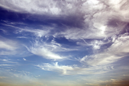 The clouds are multicolored, thunderous bizarre shapes against the blue sky and the sun above the ocean surface. The game of light and shadows in various variations of sunlight illumination of clouds and sky.の写真素材