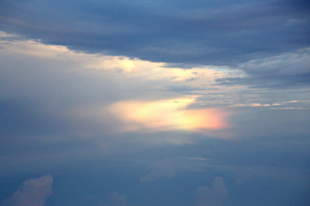 The clouds are multicolored, thunderous bizarre shapes against the blue sky and the sun above the ocean surface. The game of light and shadows in various variations of sunlight illumination of clouds and sky.の写真素材