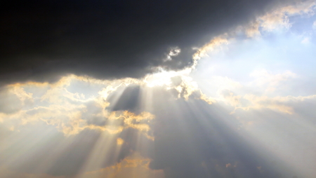 The clouds are multicolored, thunderous bizarre shapes against the blue sky and the sun above the ocean surface. The game of light and shadows in various variations of sunlight illumination of clouds and sky.の写真素材