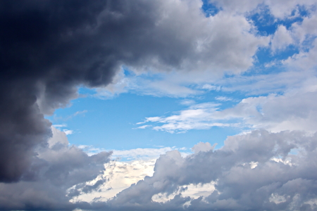 The clouds are multicolored, thunderous bizarre shapes against the blue sky and the sun above the ocean surface. The game of light and shadows in various variations of sunlight illumination of clouds and sky.の写真素材
