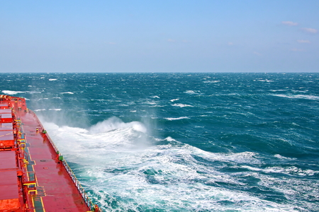 Storm waves in the world ocean. Kind of waves, crests, splashes, foam against the background of the sea horizon and the blue sky and clouds.の写真素材