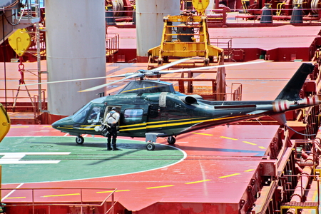 Helicopter as the main means of landing and acceptance of sea pilots for sea vessels in Australian waters, 2018. View of a helicopter close-up against a blue sky and a sea ship.の写真素材