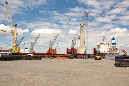 Transshipment terminal for loading steel products to sea vessels using shore cranes and special equipment. Vessels moored at berths and anchored in the roadstead. Sea and coastal line. Port Pecem, Brazil, June, 2017.の写真素材