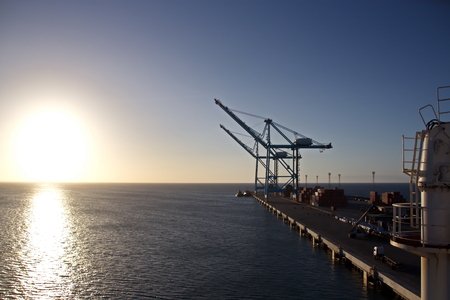 Transshipment terminal for loading steel products to sea vessels using shore cranes and special equipment. Vessels moored at berths and anchored in the roadstead. Sea and coastal line. Port Pecem, Brazil, June, 2017.の写真素材