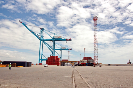 Transshipment terminal for loading steel products to sea vessels using shore cranes and special equipment. Vessels moored at berths and anchored in the roadstead. Sea and coastal line. Port Pecem, Brazil, June, 2017.の写真素材