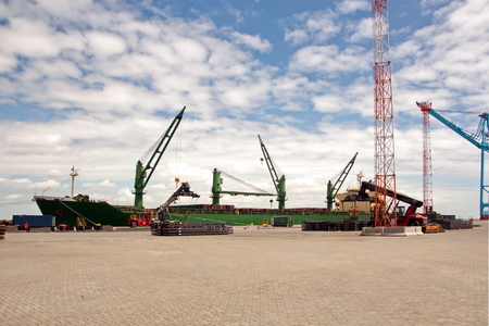 Transshipment terminal for loading steel products to sea vessels using shore cranes and special equipment. Vessels moored at berths and anchored in the roadstead. Sea and coastal line. Port Pecem, Brazil, June, 2017.の写真素材