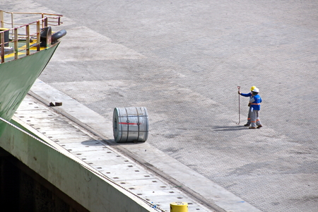 Transshipment terminal for loading steel products to sea vessels using shore cranes and special equipment. Vessels moored at berths and anchored in the roadstead. Sea and coastal line. Port Pecem, Brazil, June, 2017.の写真素材