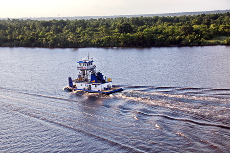 The movement of sea merchant ships and tugs to the entrance and exit from the port. View of the river Neches. Port Beaumont, Texas, USA. July 2017.の写真素材