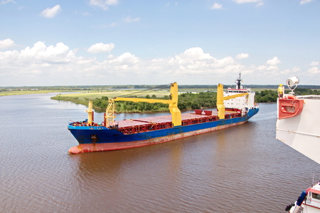 The movement of sea merchant ships and tugs to the entrance and exit from the port. View of the river Neches. Port Beaumont, Texas, USA. July 2017.の写真素材