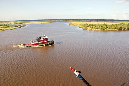 The movement of sea merchant ships and tugs to the entrance and exit from the port. View of the river Neches. Port Beaumont, Texas, USA. July 2017.の写真素材