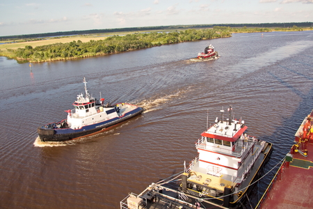The movement of sea merchant ships and tugs to the entrance and exit from the port. View of the river Neches. Port Beaumont, Texas, USA. July 2017.の写真素材